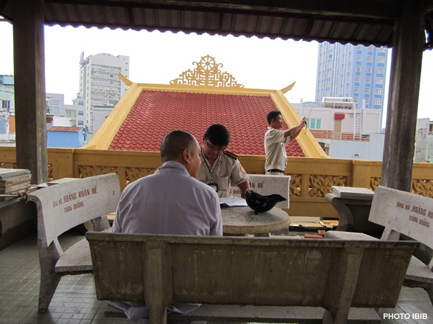 Les fonctionnaires locaux prennent des photos des travaux de renovation sur la terrasse de la Pagode Giac Hoa, le 22 mars 2012, et dresse un rapport sur les “violations des règles de construction” (Photo IBIB)