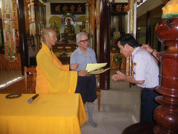 Một Huynh trưởng nhận bằng Chứng nhận hoàn mãn Trại Vạn Hạnh từ tay Thượng toạ Thích Minh Quang trước mặt Vụ trưởng Lê Công Cầu